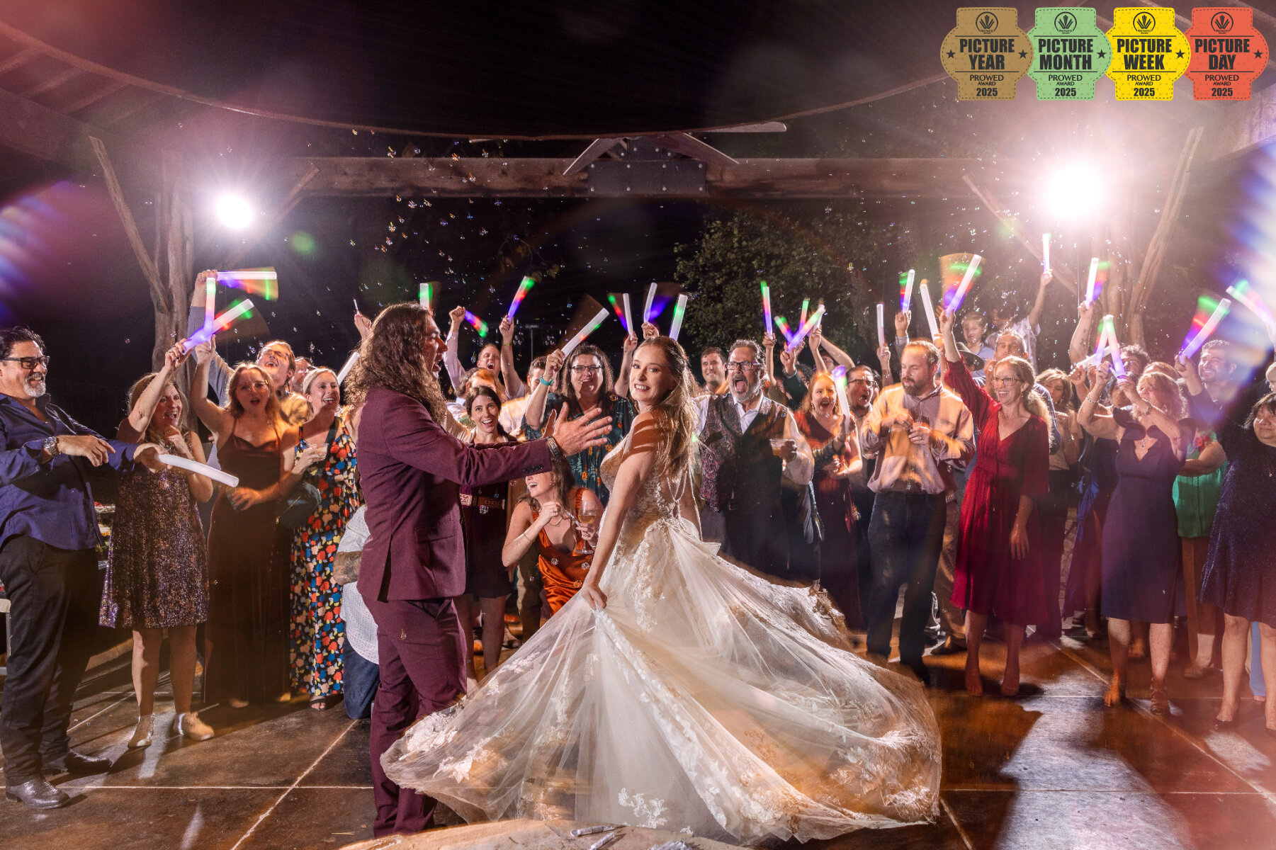 Bride twirls on dance floor surrounded by cheering guests with glow sticks during nighttime wedding celebration in the Texas Hill Country..